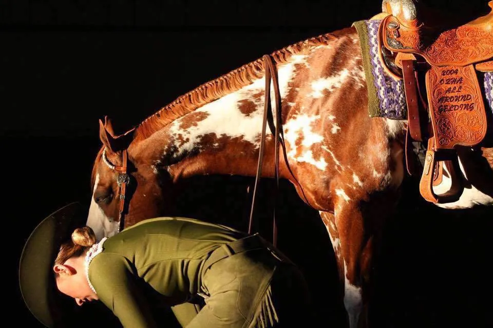 Paint horse beside a tooled western saddle
